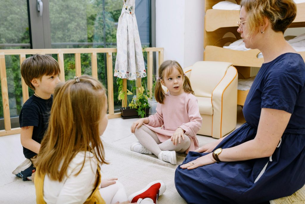 Teacher interacting with children in a cozy, educational setting.